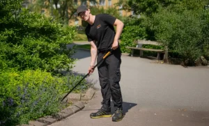 En fastighetsskötare rensar rabatter i en utemiljö