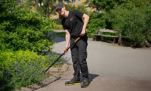 En fastighetsskötare rensar rabatter i en utemiljö